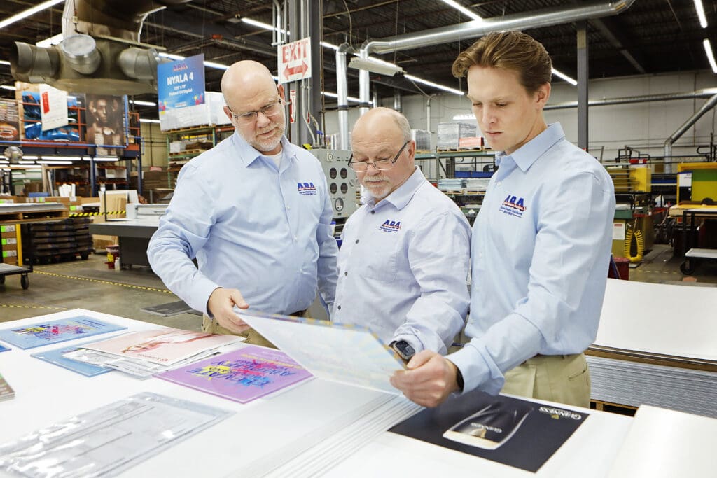 Albert Basse Associates Leadership team inspecting printed material at their facility in Stoughton, MA